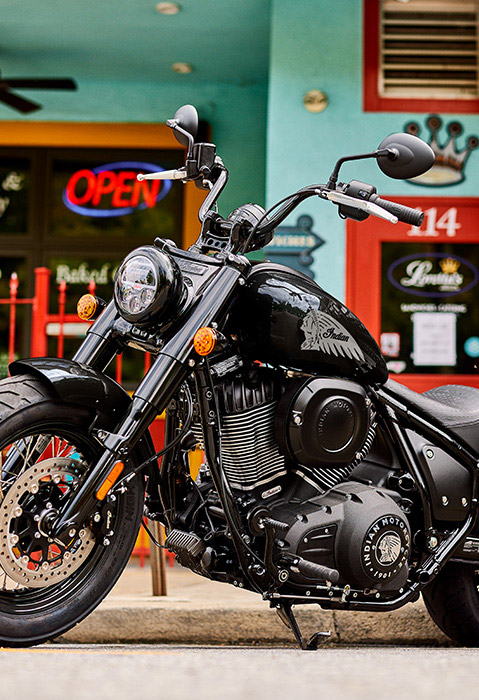 Side profile of a 2025 Indian Chief Bobber cruiser motorcycle in front of a local business.