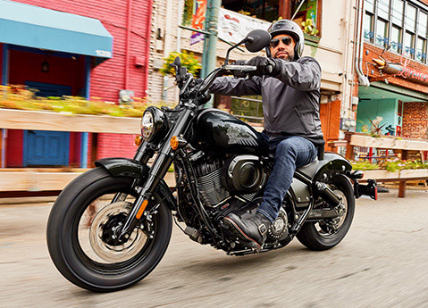 Man riding a 2025 Indian Chief Bobber cruiser motorcycle down a city street.
