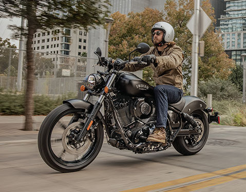 Man riding a 2025 Indian Chief Dark Horse cruiser motorcycle on a city street.