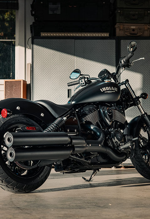 Rear/side profile of a 2025 Indian Chief Dark Horse cruiser motorcycle parked in a garage. 