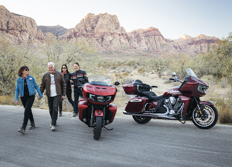 4 people walking away from a 2025 Indian Pursuit Limited motorcycle and a 2025 Indian Pursuit Dark Horse motorcycle.