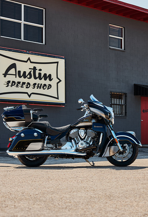 Side profile of a parked 2025 Indian Roadmaster Elite touring motorcycle in front of a building.