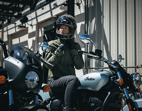 Woman putting on a helmet before a ride on her 2025 Indian Scout Sixty Classic motorcycle.