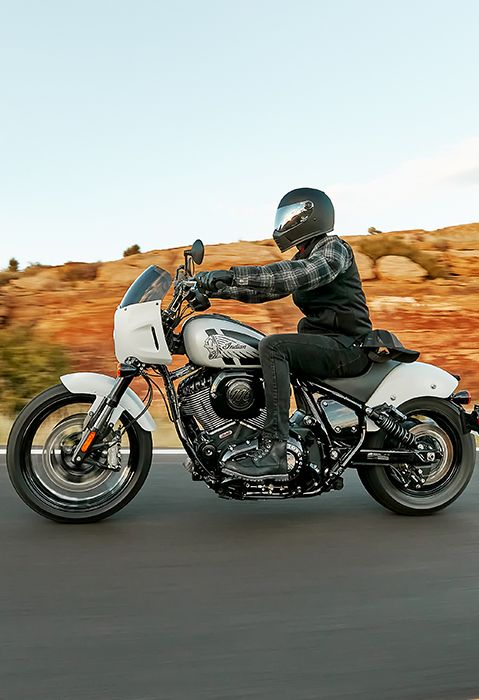 Side profile of a man riding a 2025 Indian Sport Chief motorcycle on a highway.