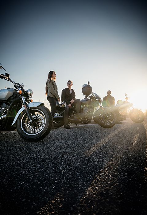 A group of friends chatting near their 3 2025 Indian Sport Scout Sixty motorcycles.