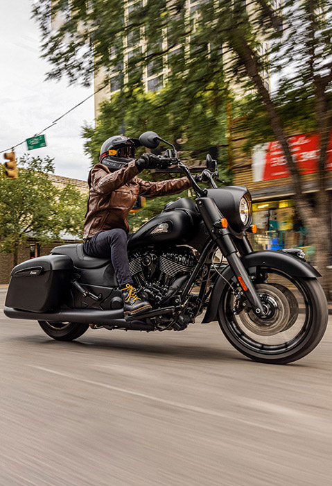 2 riders driving on a city street with their 2026 Indian Springfield Dark Horse bagger motorcycles.