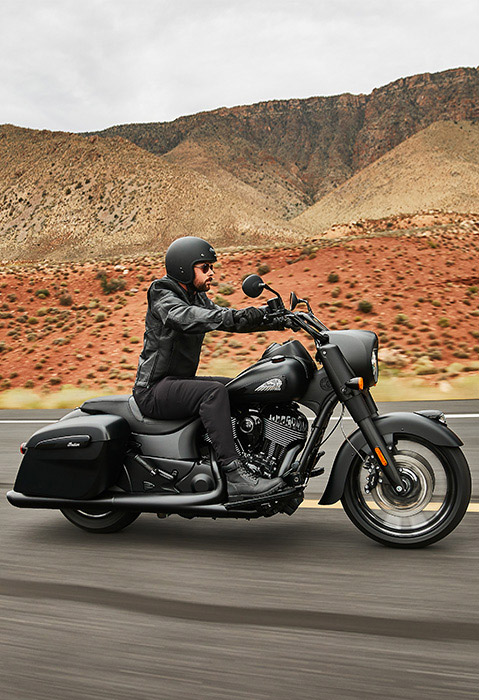 Side profile of a man riding a 2026 Indian Springfield Dark Horse bagger motorcycle on the highway. 
