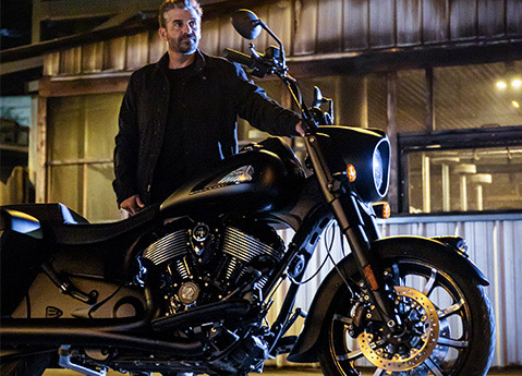 A man getting ready to ride a 2026 Indian Springfield Dark Horse bagger motorcycle at night.