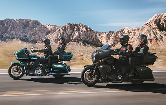 Passenger pointing over the should of driver while riding on an Indian Motorcycle. 