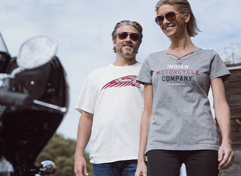 Man and woman laugh together while wearing Indian Motorcycle t-shirts. 