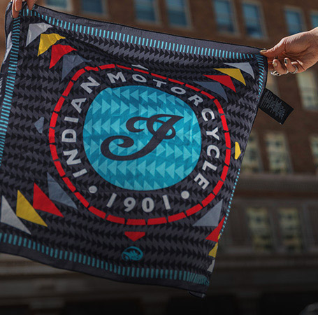 Woman holding up a Indian Motorcycle x RVSO printed bandana. 