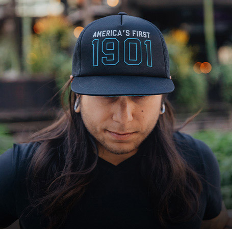 Close detail of man wearing Indian Motorcycle x RVSO printed trucker cap. 
