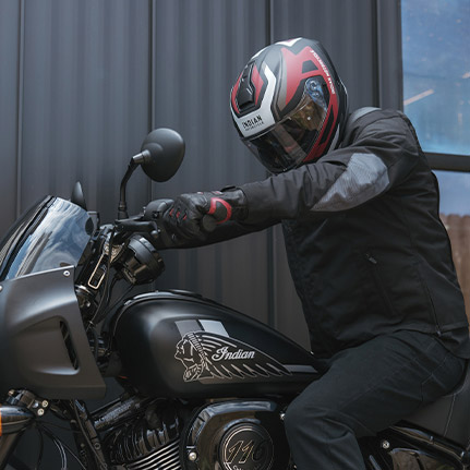 Un hombre sentado en una Indian Motorcycle, con prendas Indian. 