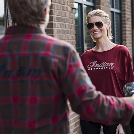 Una mujer y un hombre conversando mientras visten prendas Indian Motorcycle. 