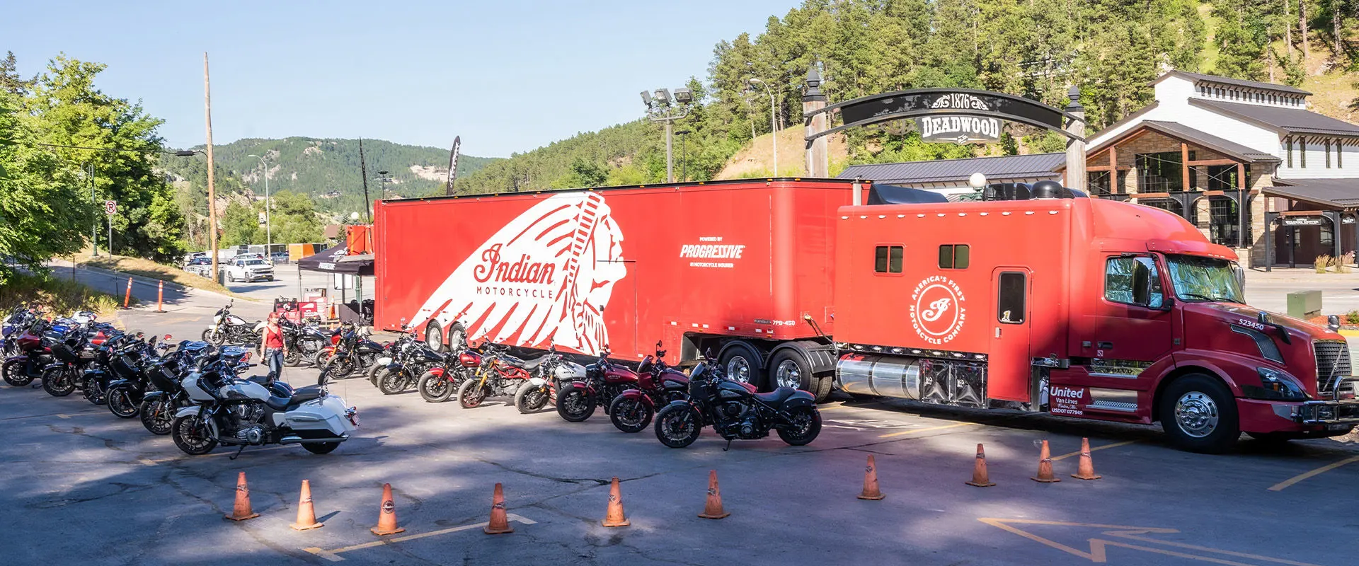 Large display of new Indian Motorcycles at Surgis Motorcycle Rally event with red Indian Motorcycle truck and trailer in the background.
