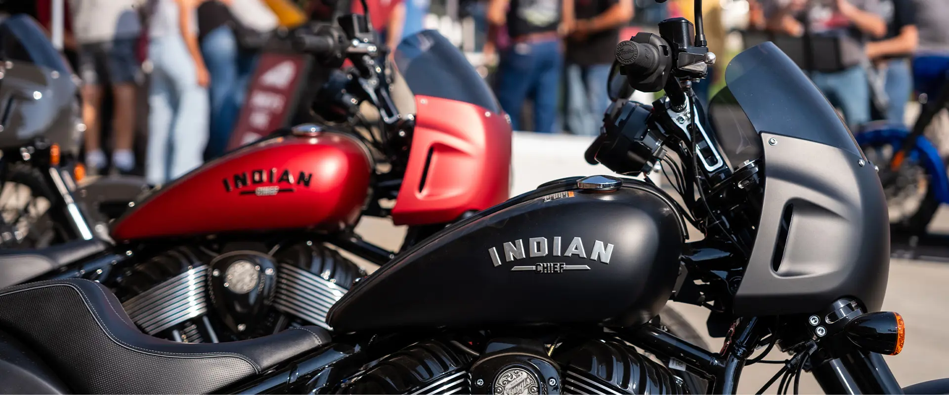 Attendees admiring custom black Indian Motorcycle at Sturgis Motorcycle Rally event, family and bikes enthusiasts present.