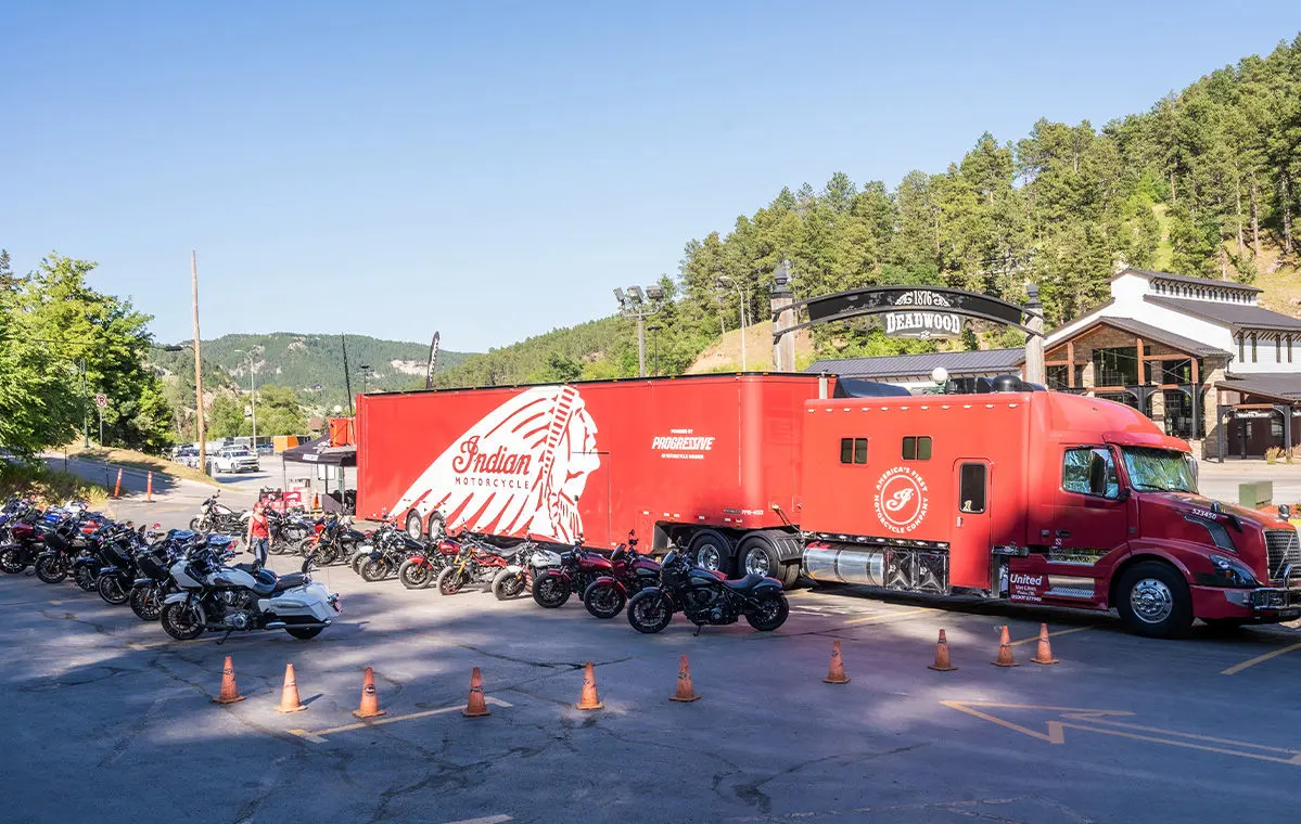 Large display of new Indian Motorcycles at Surgis Motorcycle Rally event with red Indian Motorcycle truck and trailer in the background.