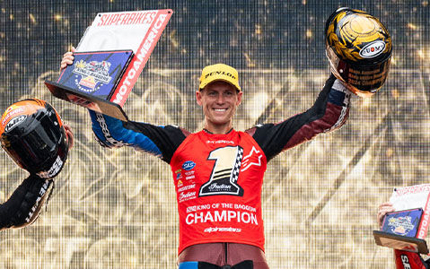 Indian Motorcycle racing crew member Troy Herfoss standing on podium with winning trophy and plaque.