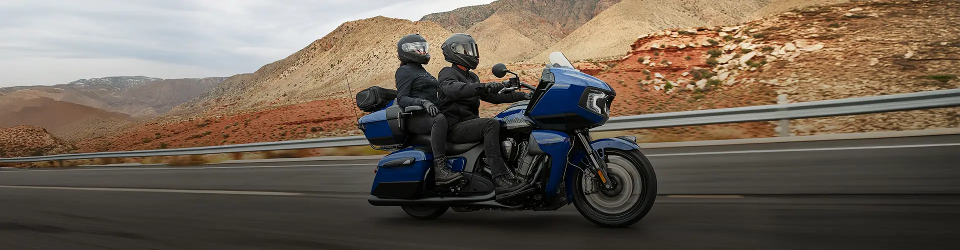 Two people riding on a blue touring motorcycle.