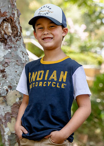 Little boy smiling while wearing an Indian Motorcycle branded shirt. 
