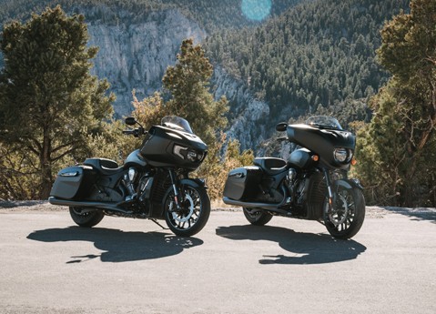 2 Dark Horse blacked-out Indian motorcycles parked with a forest in the background.