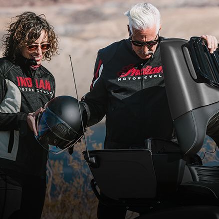 A couple grabbing gear from the ample storge of the trunk of an Indian Touring motorcycle.