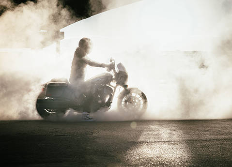 A person on an Indian Chief cruiser motorcycle surrounded in smoke.
