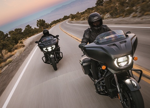 2 Indian Challenger motorcycles cruising down the highway at sunrise.