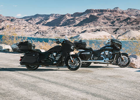 2 Indian Pursuit touring motorcycles parked by a lake.