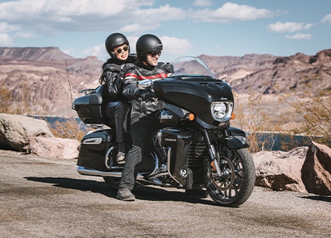 2 people with helmets on while preparing to ride an Indian Roadmaster PowerPlus touring motorcycle.