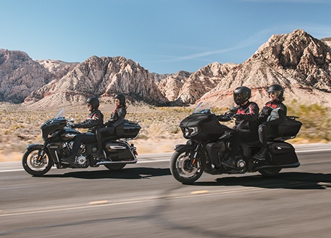 2 Indian Roadmaster touring motorcycles being driven on a desert highway.