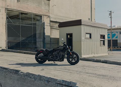 Side profile of an Indian Scout Sixty mid-size cruiser motorcycle parked in an industrial complex.