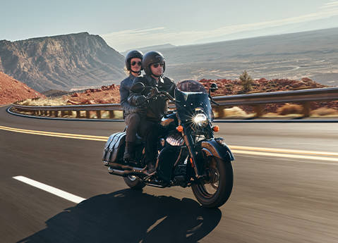 2 people riding a 2026 Indian Chief Vintage motorcycle down the highway.