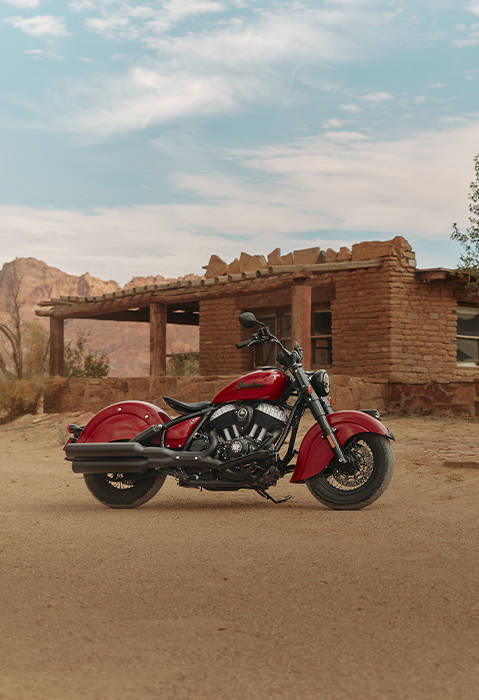 A man standing near a 2026 Indian Chief Vintage motorcycle in the desert.