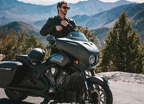 A man zipping up his coat before a ride on his 2026 Indian Chieftain PowerPlus Dark Horse bagger motorcycle.