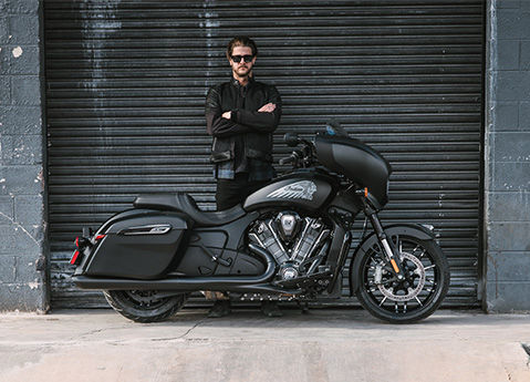A man standing with crossed arms behind a 2026 Indian Chieftain PowerPlus Dark Horse bagger motorcycle.