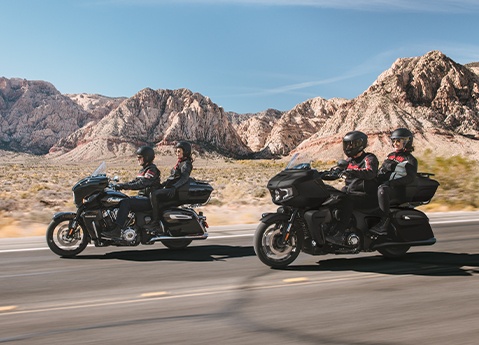 2 couples riding their 2026 Indian Roadmaster PowerPlus touring motorcycles down a desert highway.