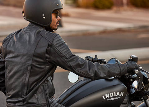 A man in a helmet and leather jacket sitting on a 2026 Indian Scout Bobber cruiser motorcycle.