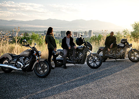 3 people sitting on and around their 2026 Indian Scout Sixty Bobber cruiser motorcycles.
