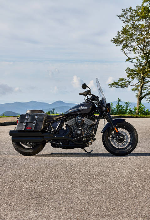 Persona de pie detrás de una motocicleta Indian Super Chief Dark Horse estilo bagger del 2025 en Black Metallic.