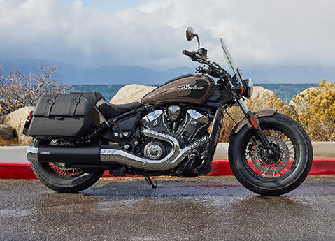 Side profile of a 2026 Indian Super Scout cruiser motorcycle with a lake in the background.