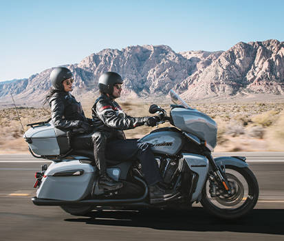 Couple riding on Indian Motorcycle through the mountains. 