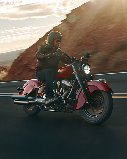 Man walking away from a parked Chief Indian Motorcycle parked in the desert. 