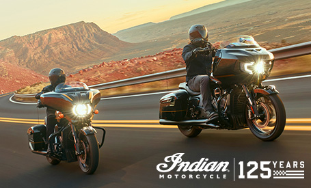 Two Indian Motorcycles riding through a desert canyon road at golden hour, featuring the 125th Anniversary logo.