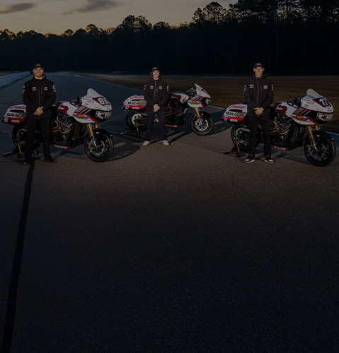 Indian Motorcycle's Wrecking Crew members: Troy Herfoss, Tyler O'Hara, and Loris Baz standing behind an Indian Challenger Motorcycle. 