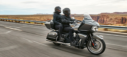 Two people riding on a black Touring motorcycle. 
