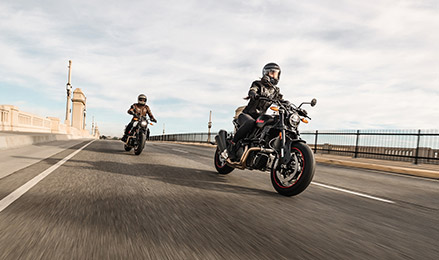 Pair of Naked Indian Motorcycles cruising on roadway.