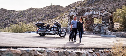 man and woman walking away from their parked indian motorcycle