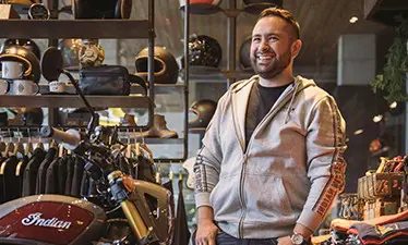 Un homme souriant devant une moto