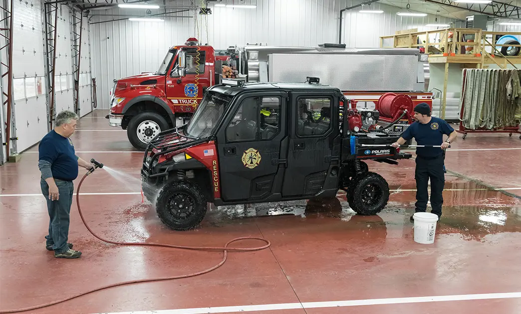 fire fighters cleaning a polaris ranger with fire & rescue package installed